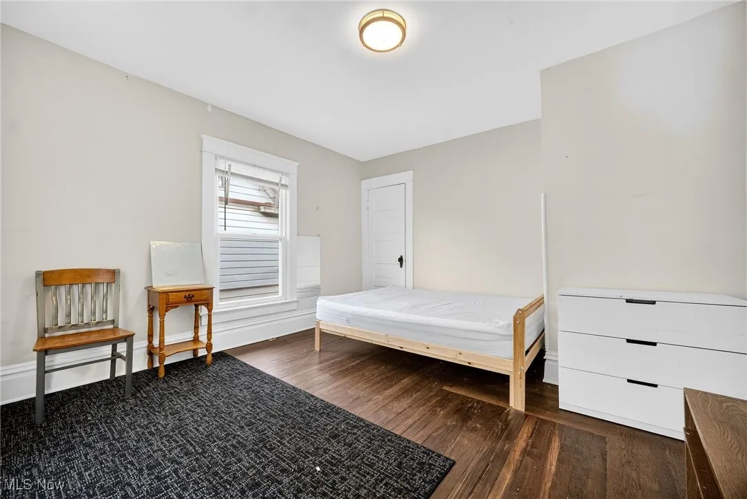 Bedroom with dark wood-style flooring and baseboards