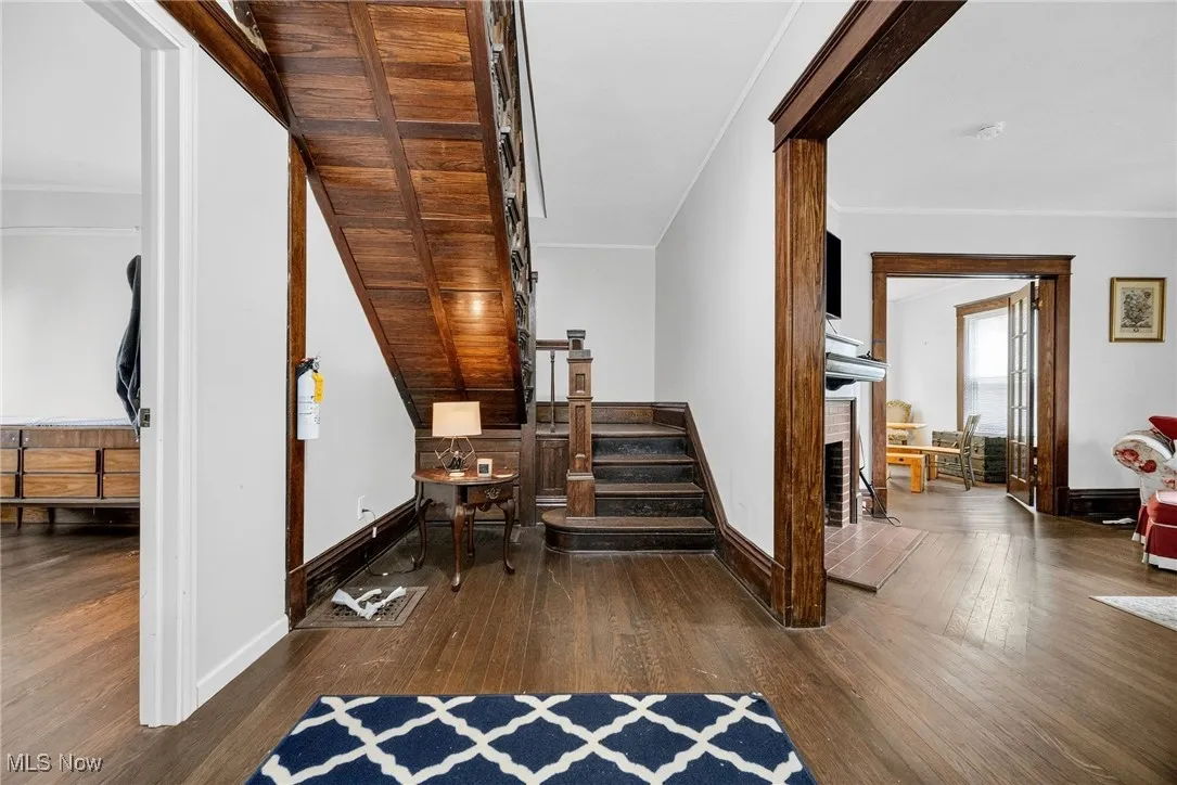 Stairway with hardwood / wood-style flooring, a brick fireplace, and ornamental molding