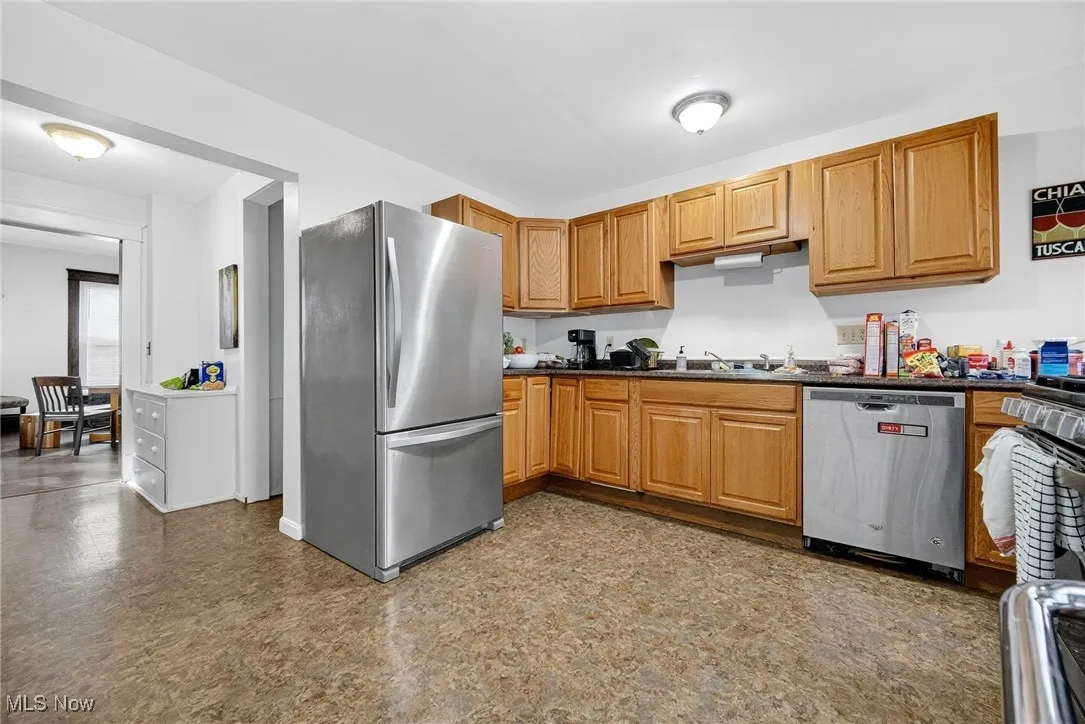 Kitchen with stainless steel appliances, dark flooring, and brown cabinets
