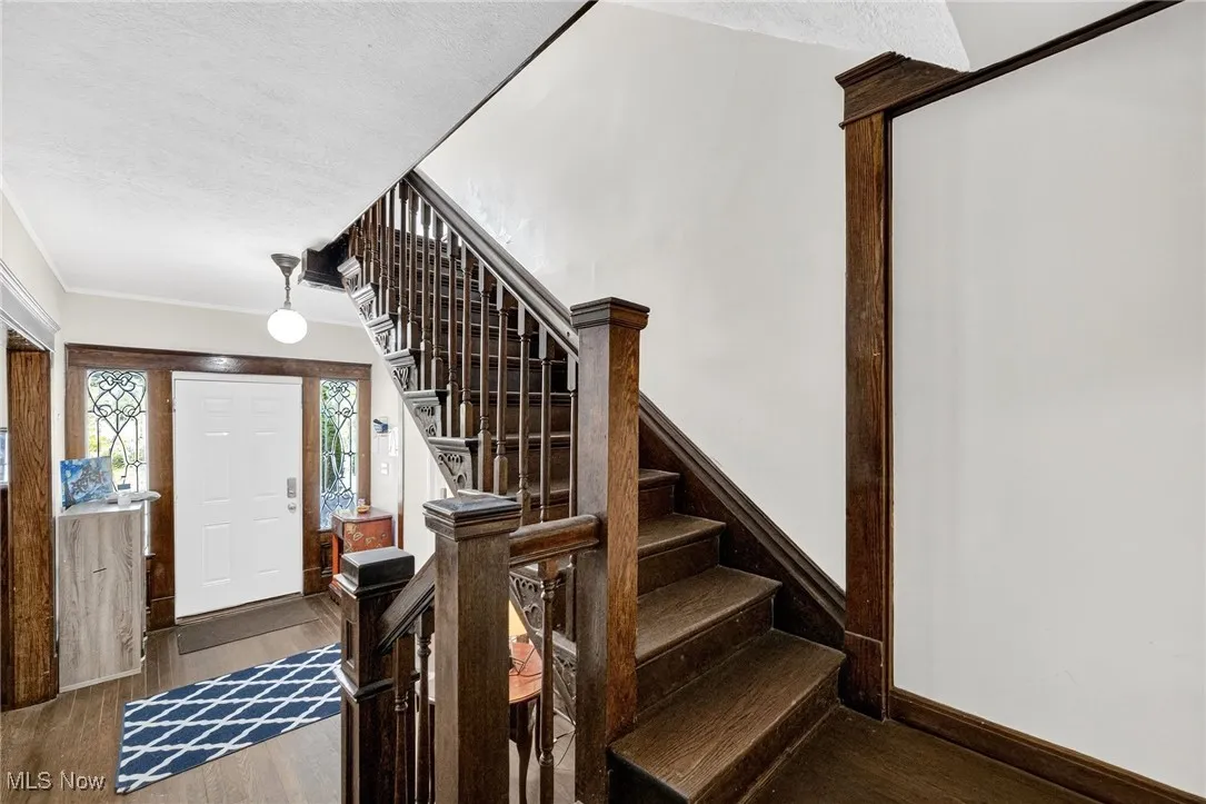 Foyer featuring wood finished floors, stairway, ornamental molding, and a textured ceiling