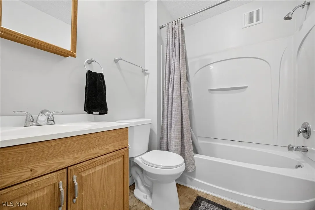 Full bath featuring shower / tub combo with curtain, vanity, and light tile patterned floors