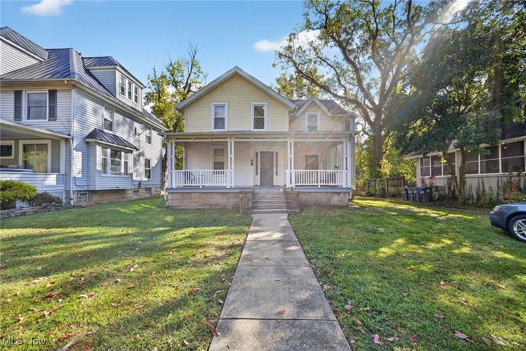 View of front of home with covered porch, a front yard, and a metal roof