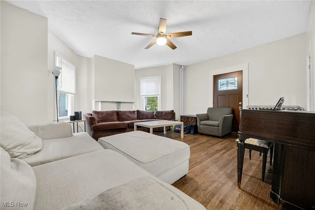 Living room featuring dark wood-style flooring, a textured ceiling, and ceiling fan