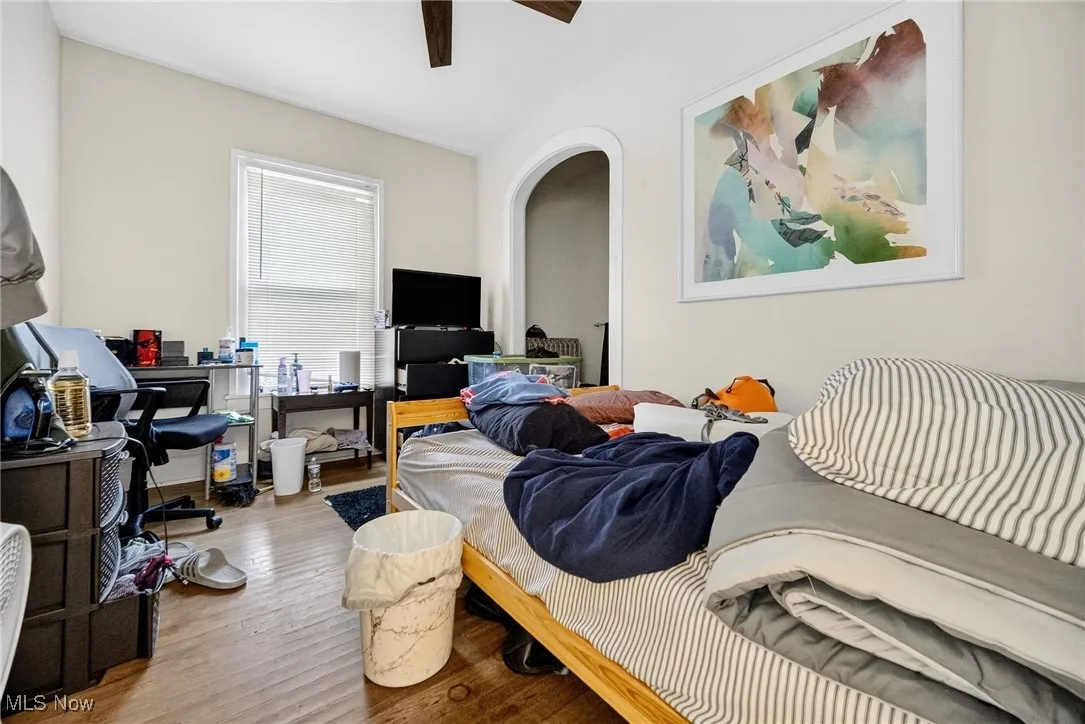 Bedroom with wood finished floors, arched walkways, and a ceiling fan