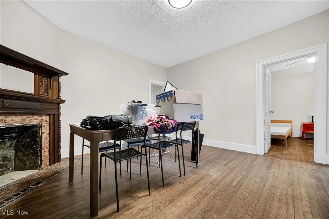 Dining room with light wood-type flooring, a textured ceiling, and a fireplace