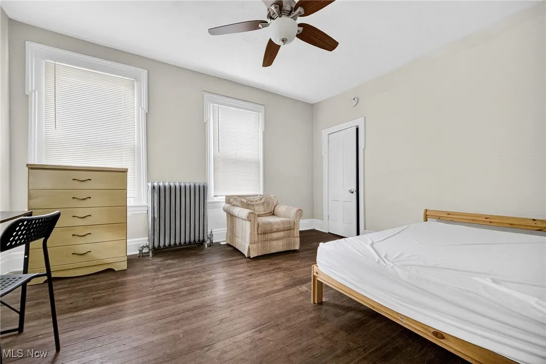 Bedroom featuring radiator heating unit, dark wood-type flooring, and ceiling fan