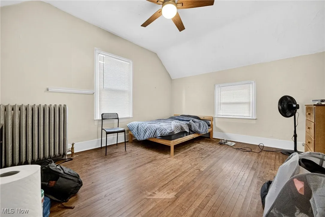 Bedroom featuring radiator heating unit, lofted ceiling, hardwood / wood-style flooring, and ceiling fan