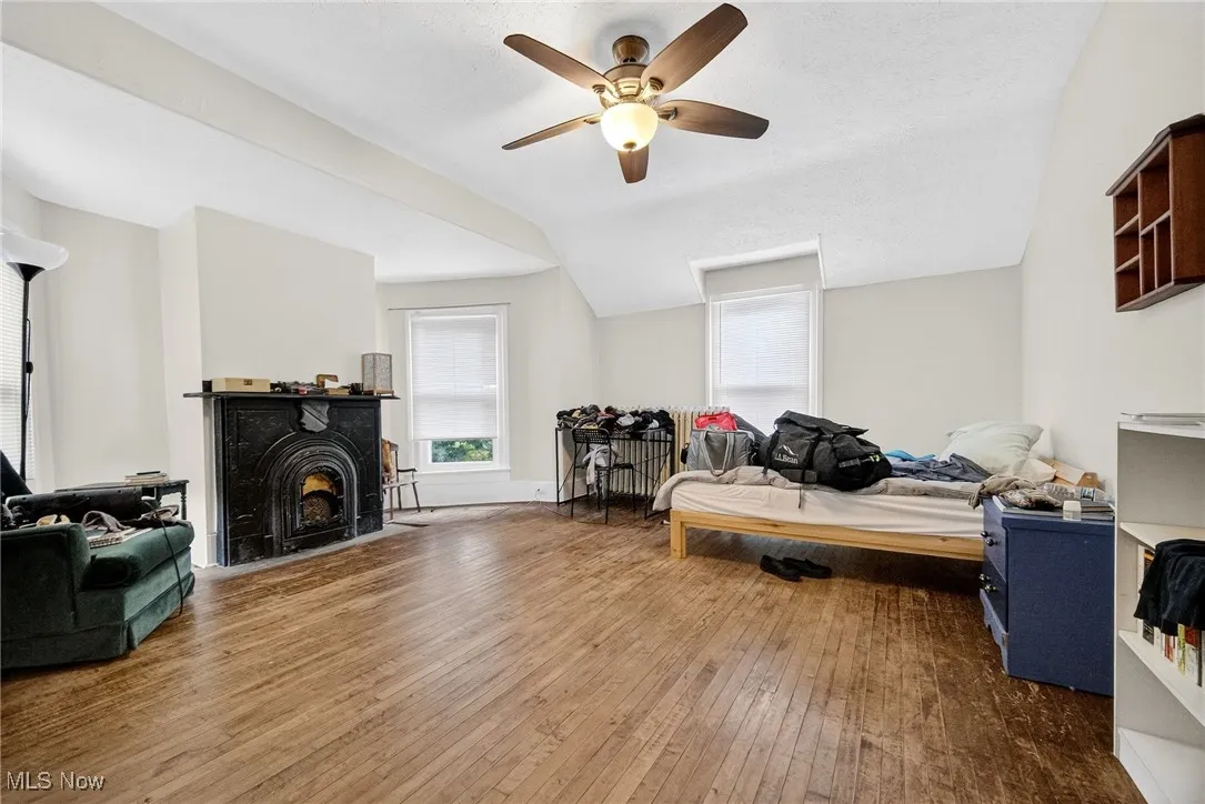 Bedroom featuring hardwood / wood-style flooring, a fireplace, ceiling fan, and lofted ceiling
