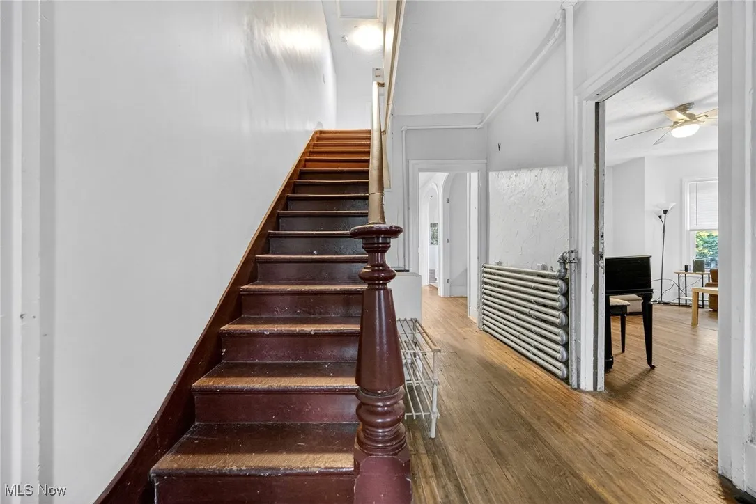 Stairs with wood finished floors and a ceiling fan