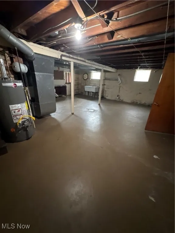 Basement with healthy amount of natural light, water heater, and heating unit