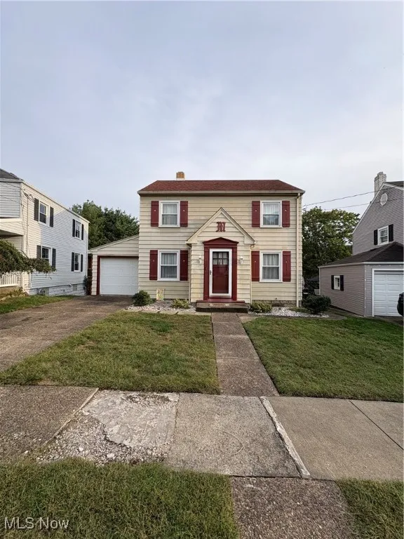Colonial-style house featuring a front yard, a garage, and driveway