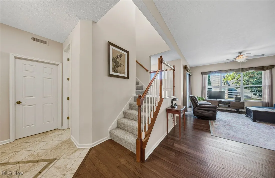 Staircase featuring wood finished floors, ceiling fan, and a textured ceiling