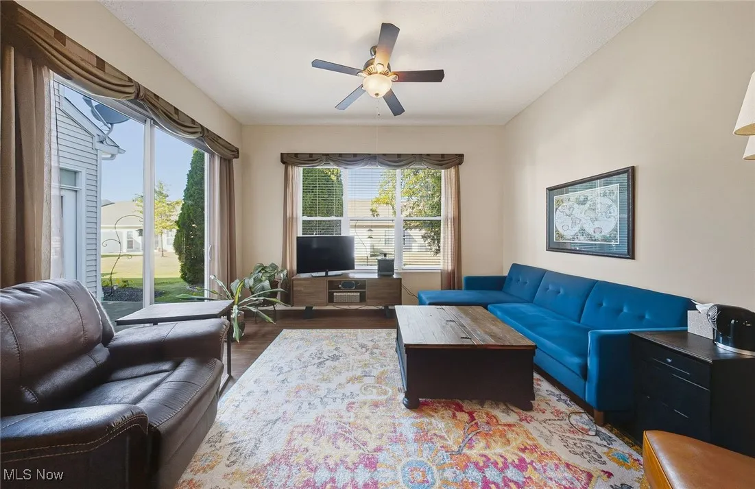 Living area featuring dark wood-type flooring and a ceiling fan