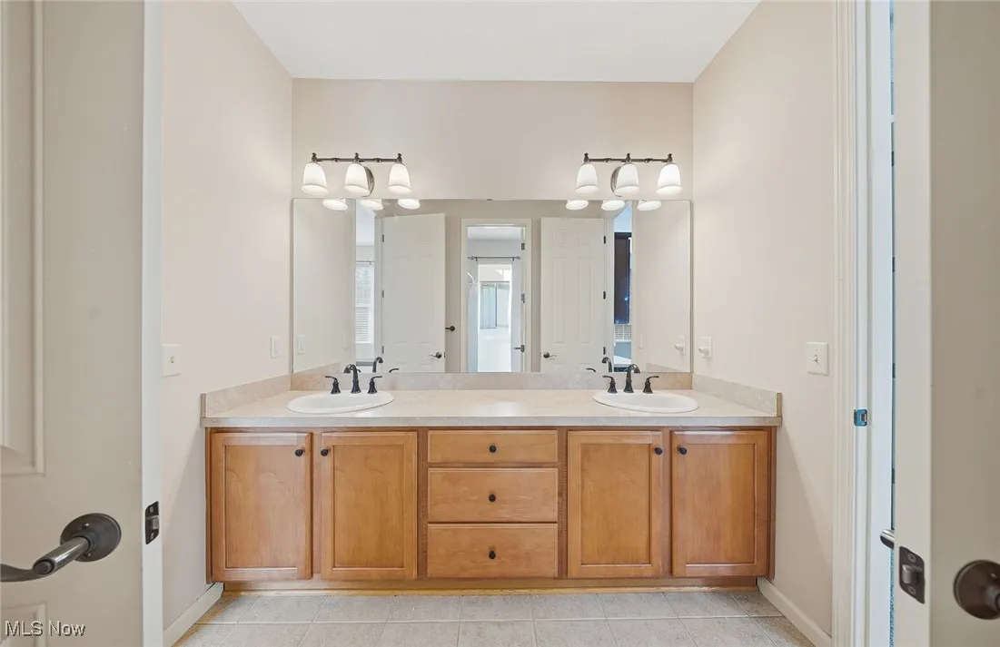 Full bath with double vanity and light tile patterned floors