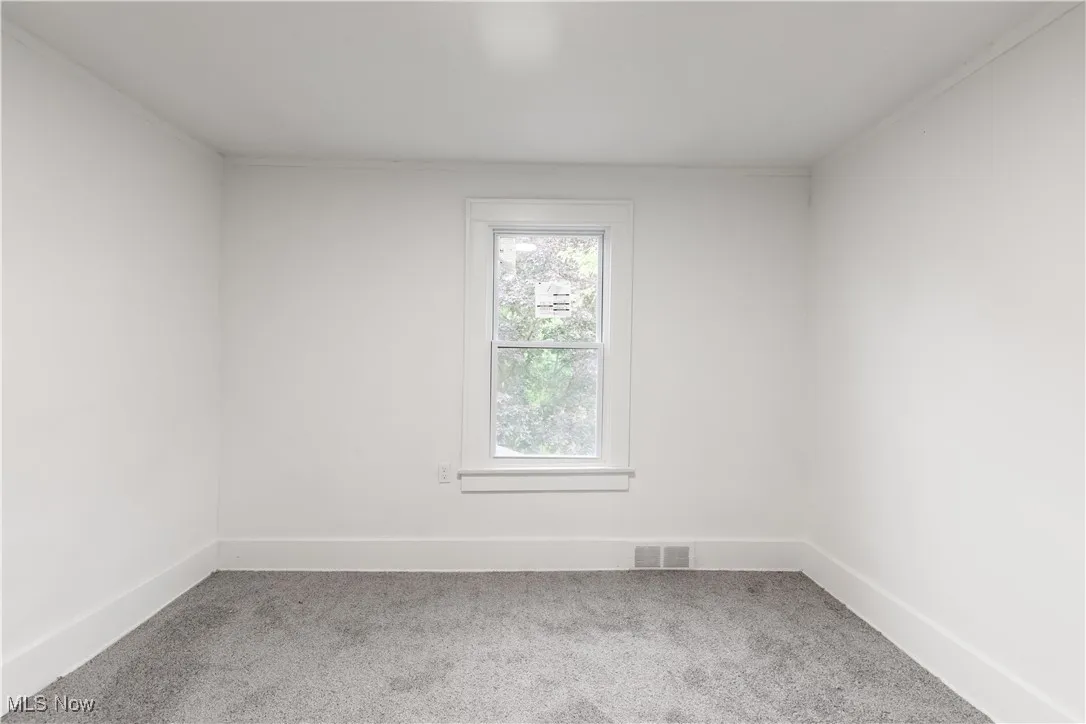 Carpeted spare room featuring baseboards