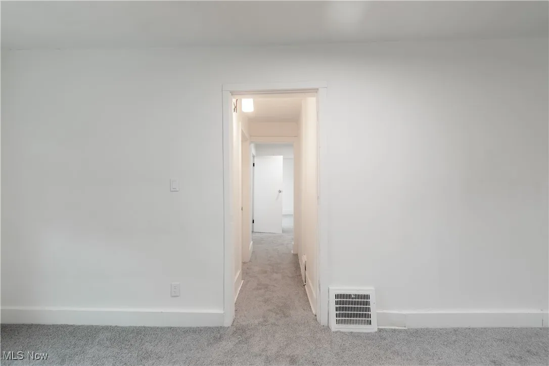 Unfurnished room featuring light carpet and baseboards