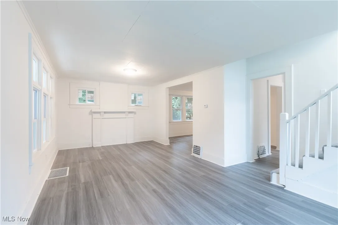 Unfurnished living room featuring stairs, wood finished floors, and healthy amount of natural light