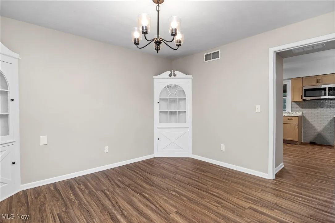 Unfurnished dining area with a chandelier and dark wood finished floors