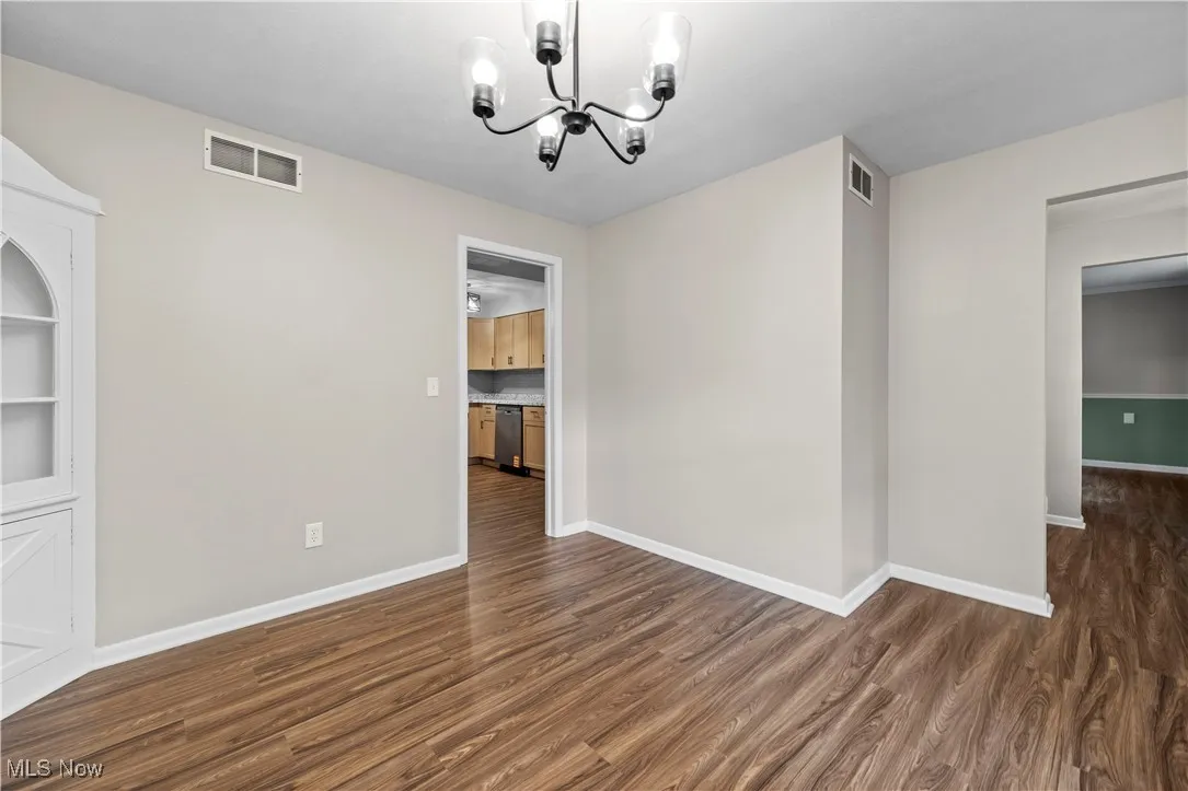 Unfurnished dining area featuring dark wood-style flooring and a chandelier