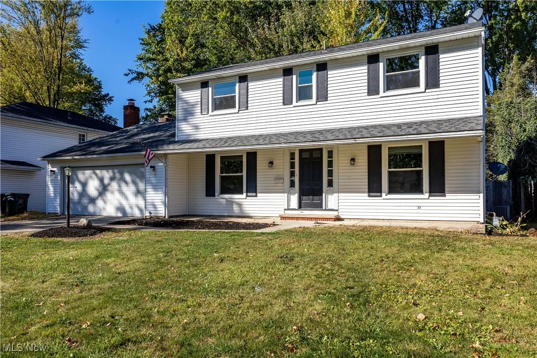 Traditional-style home with covered porch, a front lawn, an attached garage, and concrete driveway