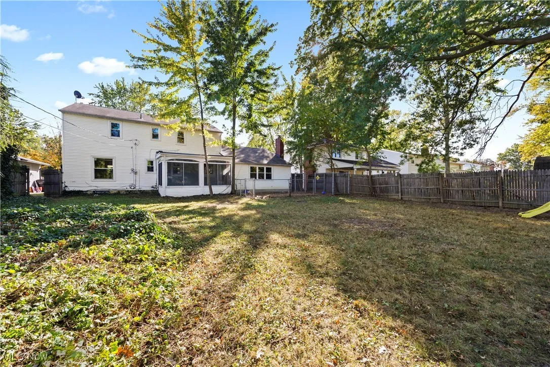 Back of property with a fenced backyard and a sunroom