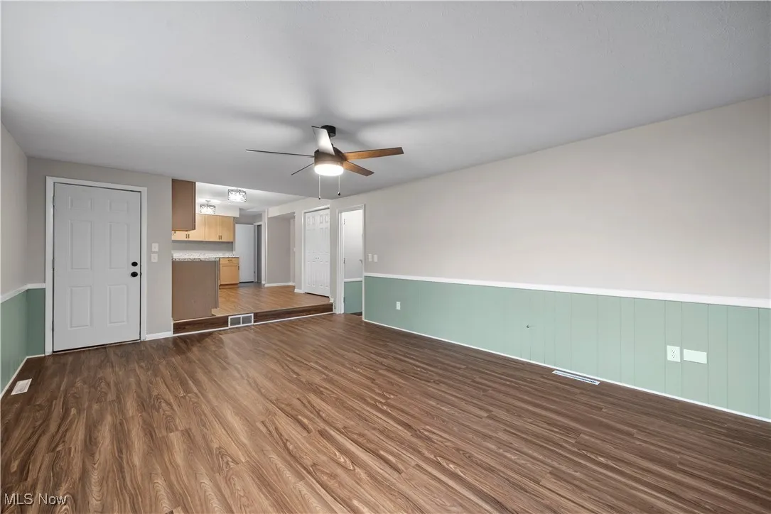 Unfurnished living room featuring dark wood-type flooring and ceiling fan