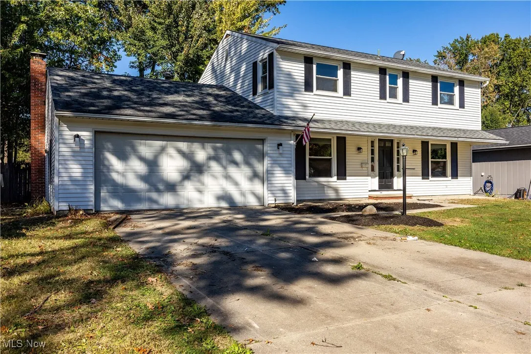 Traditional-style house with driveway, a chimney, a garage, and a porch