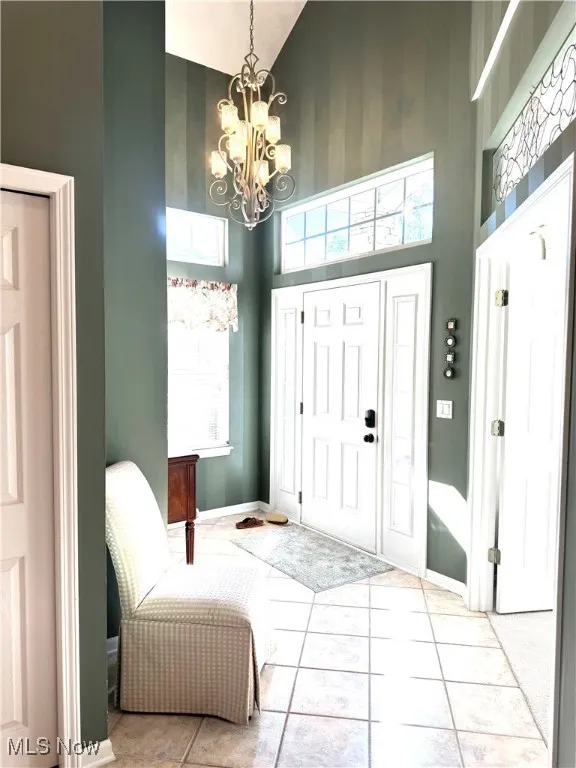 Entryway with high vaulted ceiling, a chandelier, and tile patterned floors