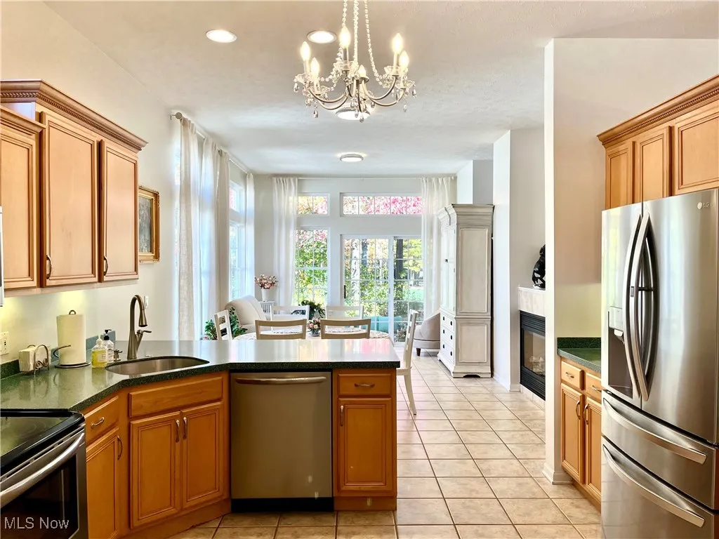 Kitchen with stainless steel appliances, a peninsula, light tile patterned floors, and pendant lighting