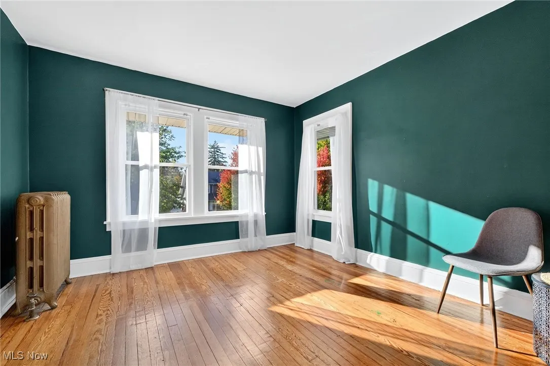 Living area with radiator heating unit, wood-type flooring, and plenty of natural light