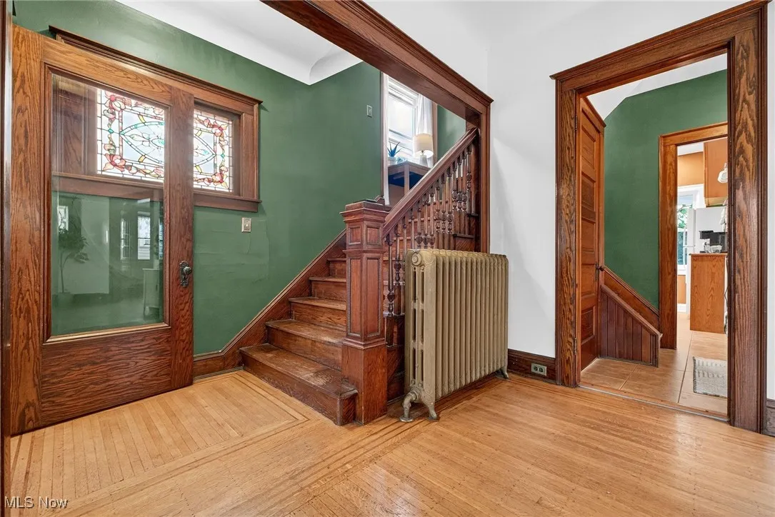 Foyer entrance featuring light wood finished floors, radiator, and stairway