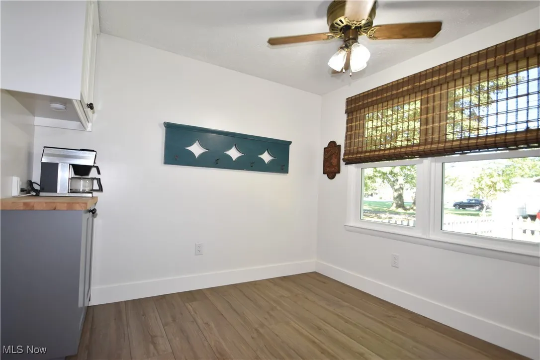 Unfurnished dining area featuring dark wood-style flooring and ceiling fan