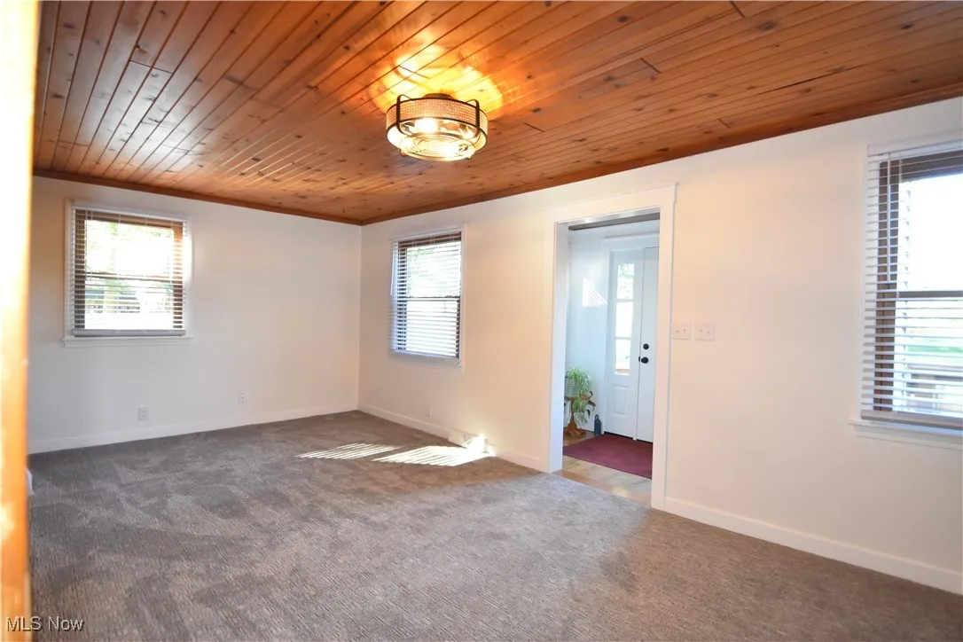 Carpeted empty room with wooden ceiling and crown molding