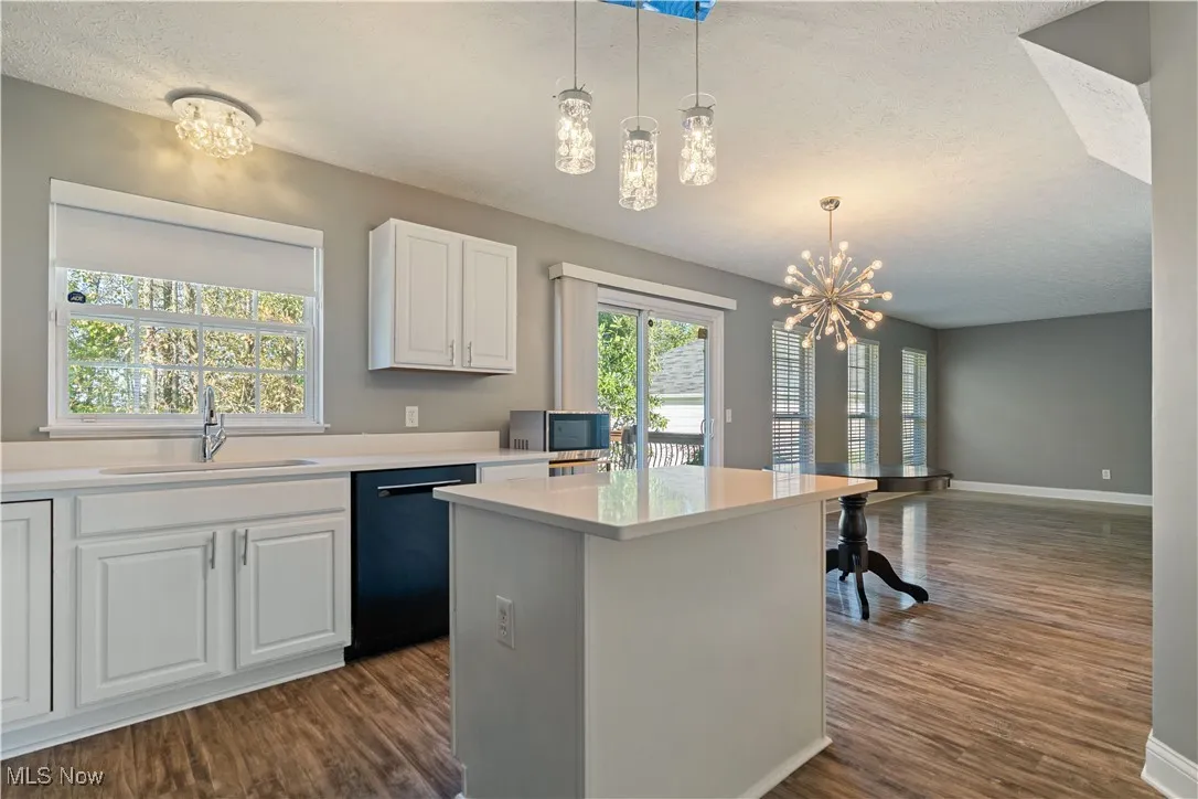 Kitchen featuring white cabinetry, pendant lighting, dark wood finished floors, plenty of natural light, and a textured ceiling