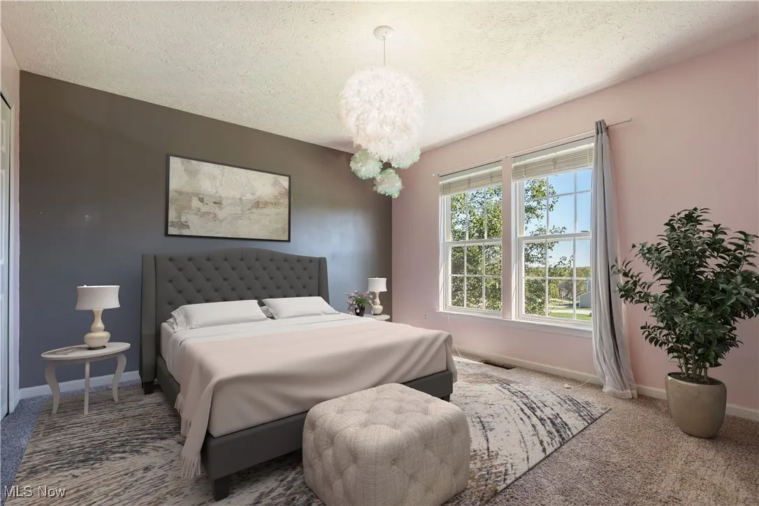 Bedroom with a textured ceiling, carpet, and a chandelier