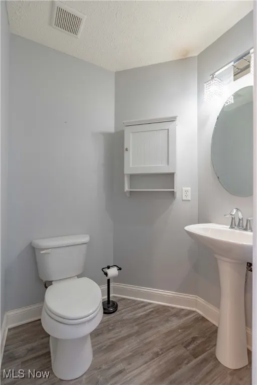Half bathroom with a textured ceiling and light wood-type flooring