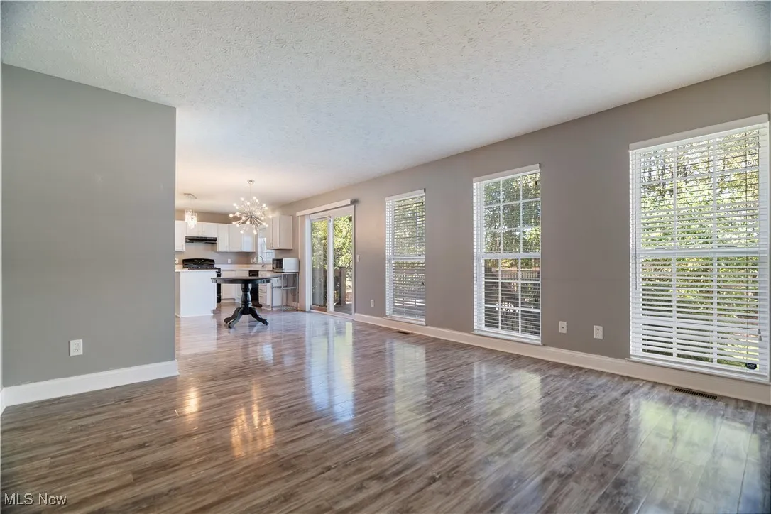 Unfurnished living room featuring a textured ceiling, dark wood-type flooring, and a chandelier