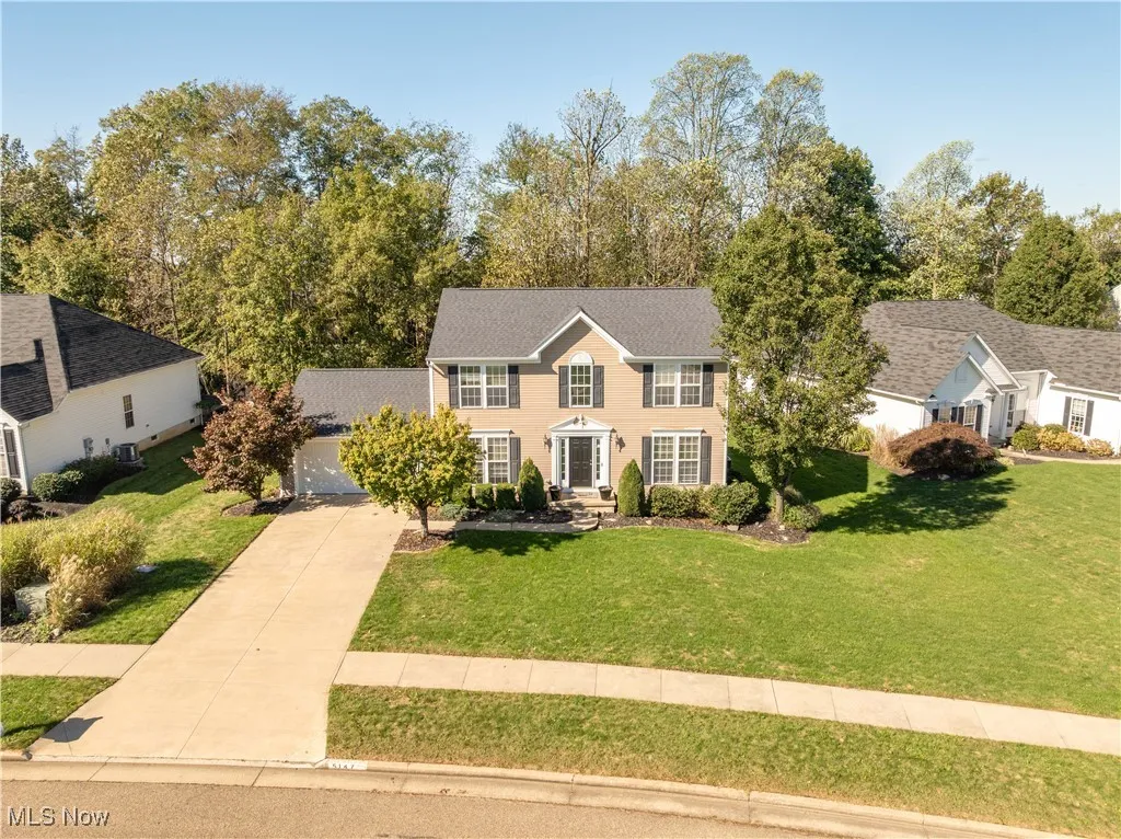 Colonial inspired home featuring a front yard, a garage, and driveway