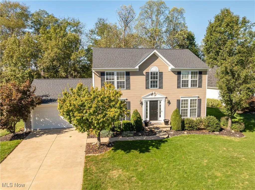 Colonial home with a front yard, a shingled roof, concrete driveway, and a garage