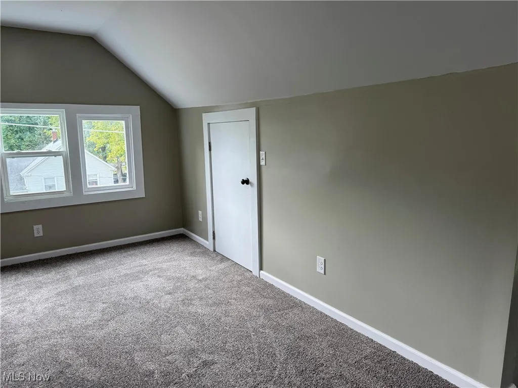 Additional living space featuring vaulted ceiling and carpet floors
