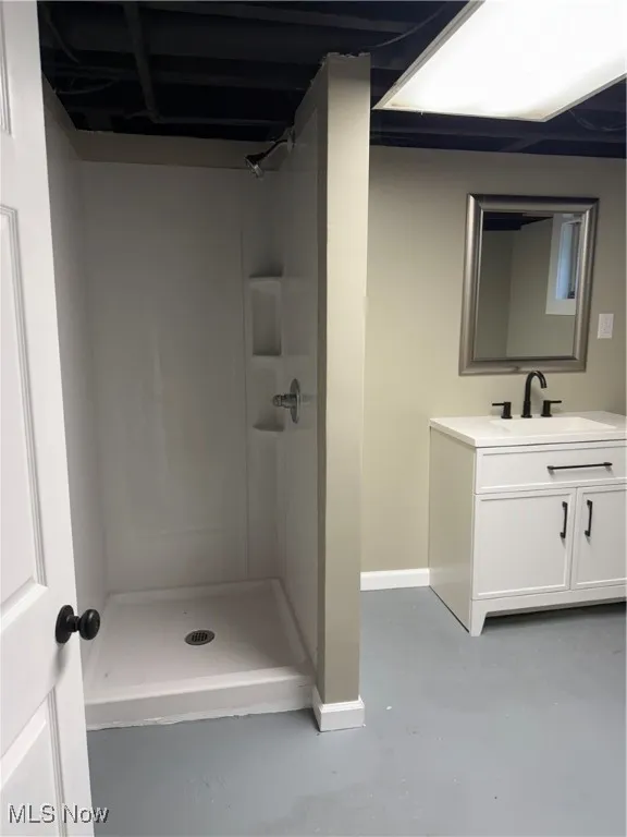 Full bath with finished concrete flooring, vanity, and a stall shower