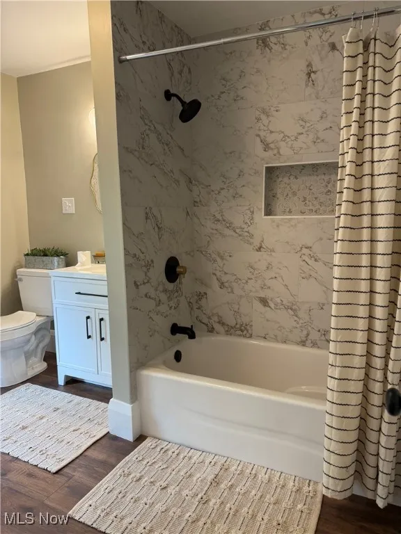 Bathroom with shower / bath combo, dark wood-type flooring, and vanity