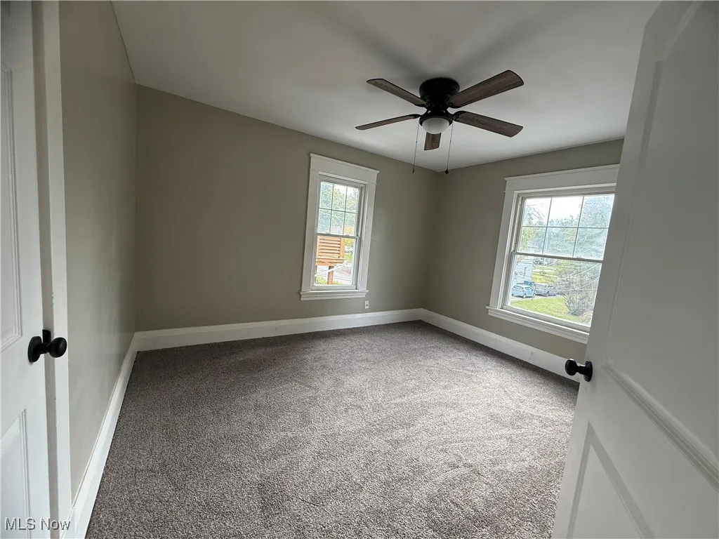 Spare room featuring light carpet, plenty of natural light, and a ceiling fan