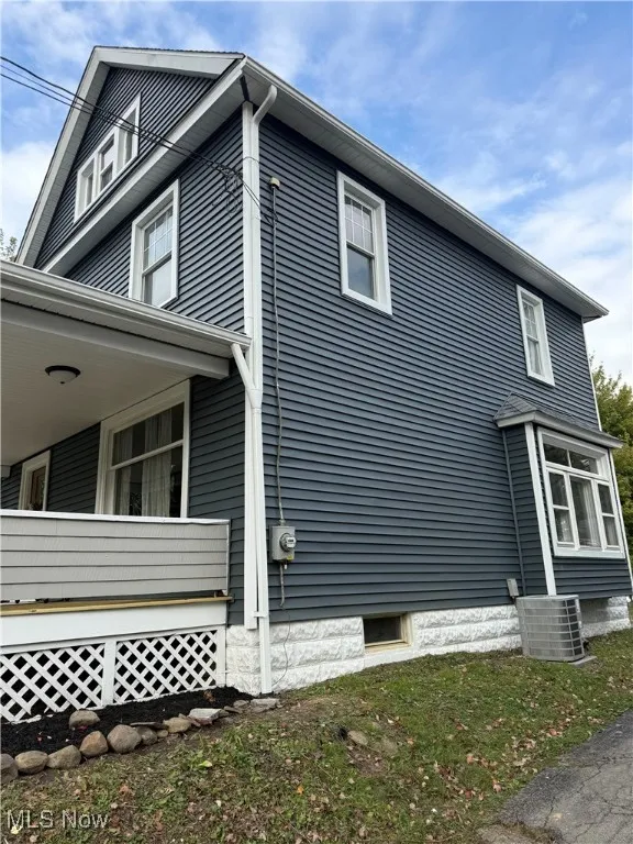 View of side of home with a cooling unit and covered porch