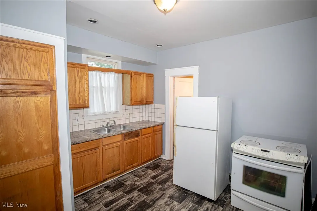 Kitchen featuring white appliances, backsplash, and brown cabinets