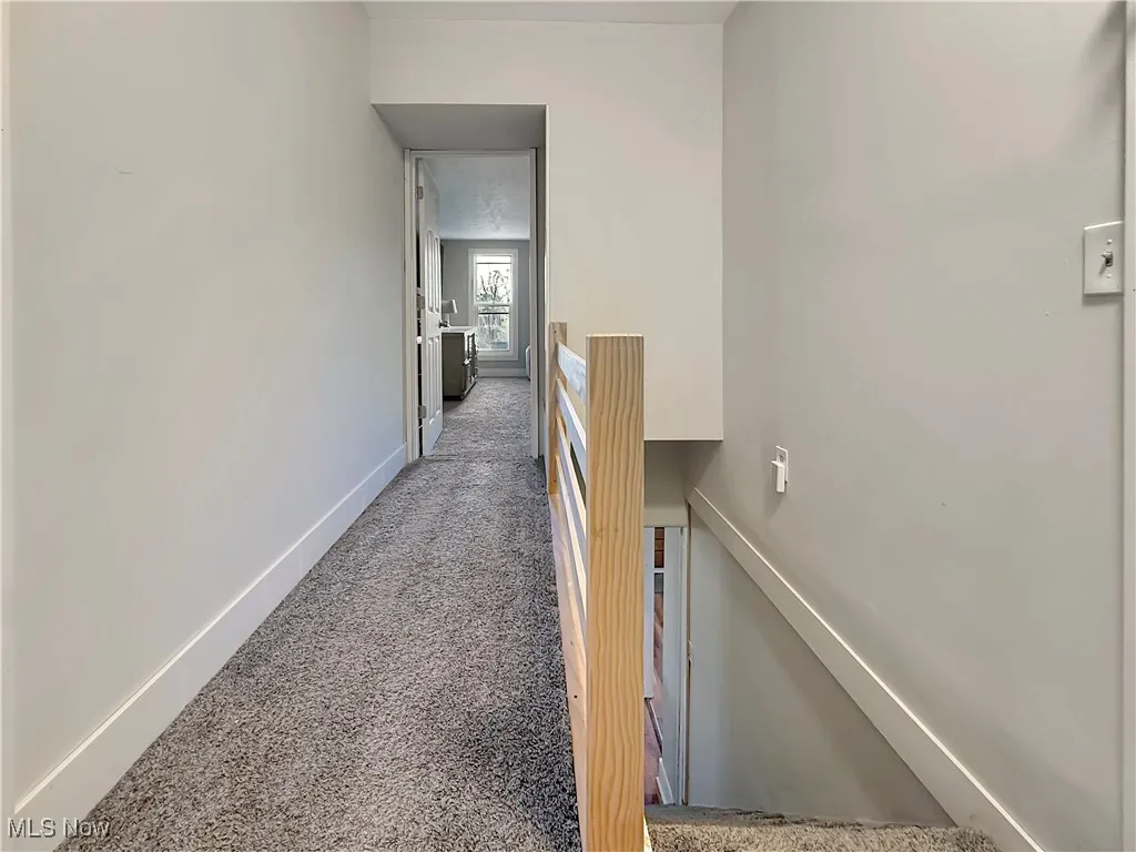 Hallway with carpet floors and an upstairs landing