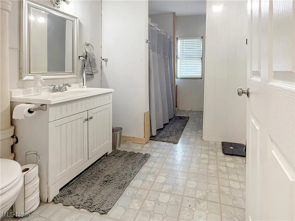 Bathroom with vanity, a shower with shower curtain, and light floors