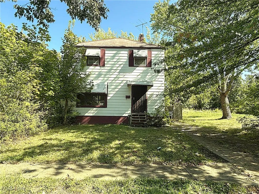 View of front facade featuring a chimney, a front yard, and entry steps
