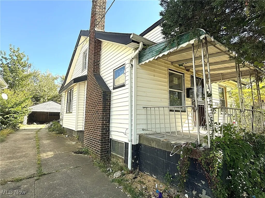 View of side of property with a chimney, covered porch, and a garage