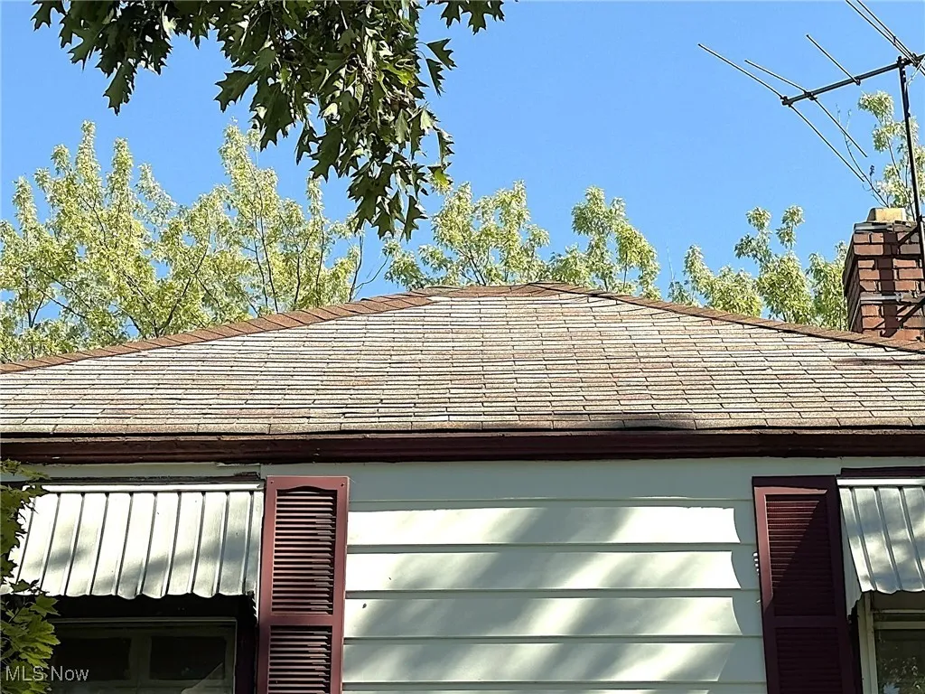 Exterior view of roof with shingles and a chimney